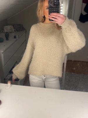 Beige stickad tröja - Supermysig beige stickad tröja med breda, långa ärmar och rund hals. Tröjan har en lite lös passform och är perr. Tröjan är från Gina men finns tyvärr inte kvar 