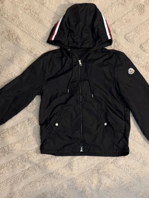 Moncler windbreaker  - Säljer en svart vindjacka i storlek XS från Moncler med huva och dragkedja. Den är helt ny och aldrig använd. Den är bästa kvalitet och NFC fungerar. Kan tänka mig att gå ner i pris vid snabb affär, kom dm!