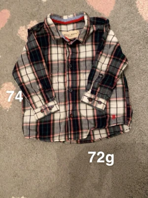 Rutig skjorta Holly & White 74 - Snygg rutig skjorta från Holly & White i storlek 74. Skjortan har långa ärmar, klassisk krage och knappar framtill. Färgerna är vit, blå, röd och grön. Perfekt för en cool och avslappnad stil.🌸 Fint använt skick. Storlek 74