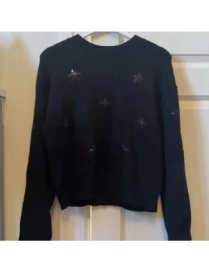 Stickad tröja från Gina Tricot💋 - Snygg svart tröja med glittrande paljettdetaljer i form av stjärnor från gina young. Tröjan har långa ärmar och en normal väldigt skön passform!! Storlek 146/152 men sitter vanligt på mig med XS/S💞