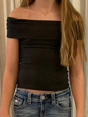 Svart offshoulder topp - Säljer en svart, croppad offshoulder topp med tight passform. Går att justera längden vid armarna.🩷