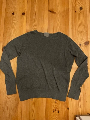 Mörkgrå stickad tröja Vero Moda XS - Mörkgrå stickad tröja från Vero Moda i storlek XS. Tröjan har rund halsringning och långa ärmar med ribbade muddar. Enkel och stilren design som funkar till många olika looks. Perfekt för kyligare dagar.