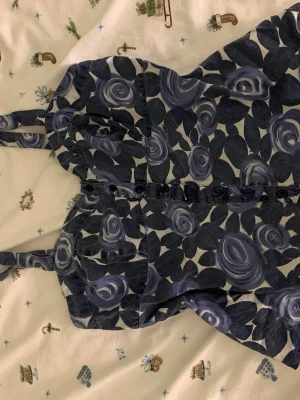 Blommig linne från Indiska - Supersöt linnetopp från Indiska med blått och vitt blommönster. Toppen har knappar framtilloch smock i ryggen. 