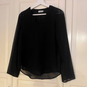 Svart blus från Lager 157 - Elegant svart blus från Lager 157 i tunn och lätt transparent tyg med ”inbyggt” linne. 