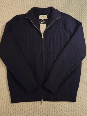 Marinblå kofta från Maison Margiela - Snygg marinblå kofta från Maison Margiela. Modellen är ribbstickad med hel dragkedja framtill och hög krage. Ställ gärma frågor! Hög kvalité. Priset är lågt för en anledning och går att diskutera 🐼