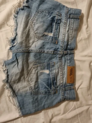 Lågmidjade shorts - Snygga Lågmidjade jeans shorts med coola slitningar och paljetter. Perfekta till sommaren 2026!                                          OBS! Några paljetter har lossat kolla bild 3.  Är köpta här på plick men är för små för mig.       Midjemåttet rakt över är 36cm!