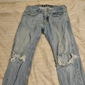 Ljusblå slitna jeans från Karve - Ljusblå jeans från Karve med raka ben och stora slitningar vid knäna för en riktigt edgy look. Klassisk femficksmodell med dragkedja och knapp. Perfekta för dig som gillar streetstyle och vill sticka ut.