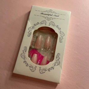 Lösnaglar i nude med glitter och stenar - Snygga lösnaglar i nude med silvriga stenar och glitterdetaljer. Innehåller flera naglar i olika storlekar, en rosa nagelfil och limkuddar. Naglarna har en elegant, avlång form och vissa har fransk tipp. Perfekt för att fixa naglarna snabbt hemma.