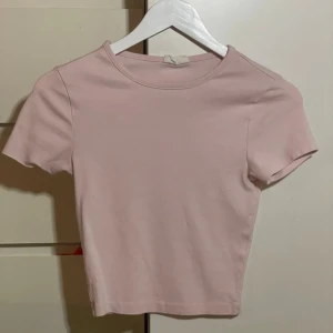 Två toppar i rosa och vitt - Säljer två stilrena croppade toppar i basic modell, en i ljusrosa och en i vit. Dem är lite korta men visar inte alls mycket mage om så önskas. Perfekta att matcha med jeans eller kjol för en enkel och snygg look. Säljer dem då dem inte används längre. Båda för 100 eller en för 75