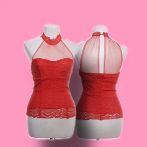 Röd spetsig halterneck topp B.Love - Supersnygg röd halterneck topp från B.Love med transparent mesh upptill och vacker spets med vågigt mönster. Toppen är figurnära och har hög hals med knäppning i nacken. Perfekt för dig som vill sticka ut med en feminin och trendig look.