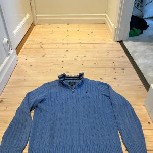 Blå stickad half zip från Polo Ralph Lauren - Säljer en blå kabelstickad tröja från Polo Ralph Lauren med half zip och hög krage. Tröjan har lång ärm, ribbade muddar och den klassiska broderade loggan på bröstet. Perfekt för dig som gillar stilren och tidlös design. Den är i mycket fint skick och är i storlek 14-16 vilket är runt xs. Modellen är 175!  Priset är inte hugget i sten😇💸 Skriv vid andra funderingar!   MVH //Alve