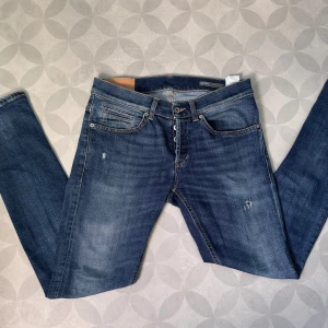 Dondup George st. 31 - Snygga blå jeans från Dondup i klassisk femficksmodell. Jeansen har en lätt tvättad look med diskreta slitningar och orangea sömmar. Modellen har raka ben och normal passform, perfekt till sneakers eller boots. Materialet är mjukt och följsamt jeans.