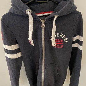 Mörkblå Superdry zip hoodie  - Mörkblå zip hoodie från Superdry i storlek S, modellen är ca 180cm. Hör av dig vid funderingar!