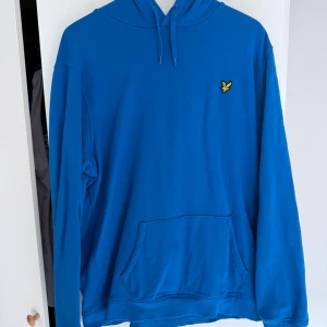 Två Lyle & Scott hoodies XXL - Säljer två feta hoodies från Lyle & Scott i storlek XXL. En är klarblå och den andra ljusgrå, båda med klassisk gul fågel-logga på bröstet och känguruficka. Perfekta för chill eller streetstyle. Mjukt bomullsmaterial och sköna huvor med snörning.