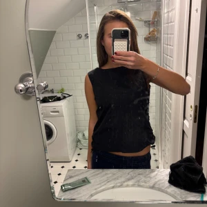 Svart ärmlös topp från InWear - Svart ärmlös topp från InWear i stilren design. Toppen har rund halsringning och dragsko med snörning i sidorna för en justerbar passform. Tillverkad i ett slätt, lätt material som känns bekvämt mot huden. Perfekt att styla med jeans eller kjol.