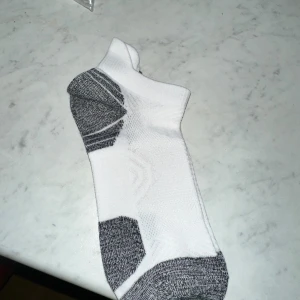 Gråa och vita korta stödstrumpor  - Stimulerar blodcirkulationen: Effektiviserar transporten av syrefattigt blod tillbaks till hjärtat och minskar trötthet, svullnad och ömhet i benen. Förebyggande: Regelbundet användande minskar risken för att drabbas av åderbråck och andra venösa besvär.Användningsområden: Används med fördel dagligen. Passar utmärkt för dig som står upp/sitter ner under långa perioder i arbetet, för dig som ska resa långt och för dig som är gravid.