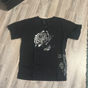 Vlone x tupac shoot for the stars aim for the moon - Svart vlone tröja med tupac tryck och text på baksidan och ros tryck på framsidan.