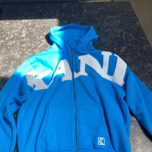 Blå hoodie från Karl Kani med logga - blå hoodie storlek M. Har aldrig använts pga att den är förstor. inga repor eller liknande skavanker, fint skick ingen tappad färg