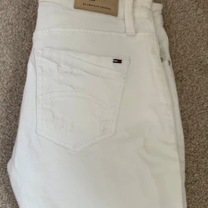 Vita slim jeans Hilfiger Denim - Snygga vita jeans från Hilfiger Denim, modell Naomi. De har midwaist passform, är slim och 7/8-långa med slitna detaljer längs benen. Klassisk femficksdesign, stretchigt bomullsmaterial och diskret Hilfiger-logga på fickan. Perfekta för en trendig look.