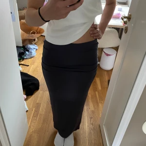 Svart långkjol från Gina Tricot - Säljer en svart långkjol från Gina Tricot i mjukt och stretchigt material. Kjolen har en tight passform och hög midja, perfekt för en clean och stilren look. Enkel design utan mönster eller detaljer, passar till många olika outfits.