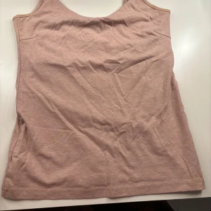 Rosa linnetopp från 157 med smala band - Säljer en enkel och stilren beige linnetopp från 157 med smala axelband och rundad halsringning. Toppen är tillverkad i en mjuk bomulls- och polyestermix som känns skön mot huden. Perfekt att matcha med jeans eller kjol för en avslappnad look.