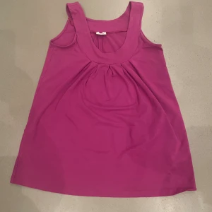 Rosa ärmlös linnetopp från Kanok - Snygg rosa linnetopp från Kanok med breda axelband och rundad halsringning. Toppen har fina veck framtill som ger en avslappnad och luftig känsla. Superfin och i toppen kvalite