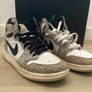 Nike Air Jordan 1 Elephant Print - Säljer ett par Nike Air Jordan 1 med unik elephant print i beige och svart, vita paneler och svarta swoosh. Skorna har högt skaft, snörning och olika färg på skosnörena. Kommer med originalbox med klassisk Jumpman-logga.