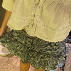 Blommig blå volangkjol - Supersöt kort kjol med blått och vitt blommönster och volangdetaljer. Kjolen har en luftig känsla och passar perfekt till varma dagar. Resår i midjan för skön passform. Använt fåtal gånger💞