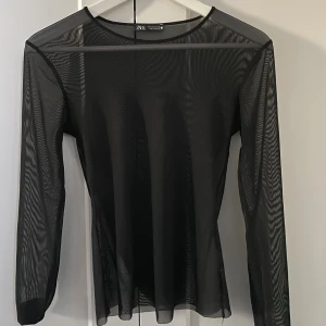 Svart mesh topp från Zara - Säljer en svart mesh topp från Zara med lång ärm och rund halsringning. Toppen är helt genomskinlig och har en tight passform.