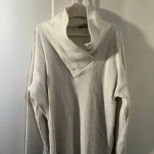 Vit ribbad polotröja med v-ringning - Säljer en vit ribbad polotröja med bred krage och v-ringad hals. Tröjan har lång ärm och är tillverkad i ett mjukt, stickat material som passar till hösten