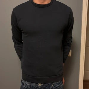 Mörkblå Colmar sweatshirt  - Säljer en stilren mörkblå sweatshirt från Colmar med rund hals och diskret logga på ärmen. Tröjan är i mjuk bomull och har en klassisk passform med långa ärmar. Perfekt för dig som gillar enkel och clean stil.