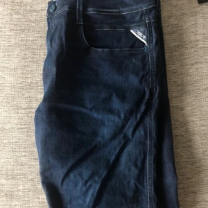 Replay Anbass slim fit jeans blå - Säljer ett par mörkblå Replay Anbass slim fit jeans i storlek W36 L34. Klassisk femficksmodell med snygg passform och diskret Replay-logga vid fickan. Jeansen är tillverkade i stretchigt denim för extra komfort och stil. Jeansen är oanvända, modellen är 189cm lång och väger 70kg