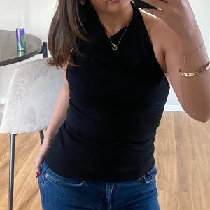 Svart halterneck topp med drapering och öppen rygg - Säljer en svart halterneck topp med snygg drapering framtill och öppen rygg. Jättemjukt och tjockt material. Dubbeltyg vid brösten. Använd en gång💓