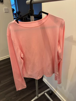 Ljusrosa långärmad topp - Säljer en ljusrosa långärmad topp med rund hals. Toppen har en enkel och clean design utan mönster eller detaljer, perfekt för dig som gillar en soft och chill stil. Materialet känns mjukt och lätt mot huden, vilket gör den skön att bära.