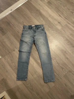 Loose fit Jack and Jones jeans i ljusblå denim - Loose/Chris Jack and Jones jeans i ljusblå tvättad denim med klassisk femficksdesign och raka ben. Skön loose passform som ger en avslappnad vibe. Perfekt för dig som gillar lite bredare jeans och vill ha en chill stil.