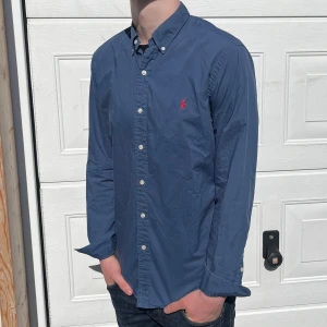 Blå Ralph lauren skjorta - Säljer nu min riktigt fina Ralph sluten skjorta i jätte fint skick, bara att skriva vid funderingar, fraktas inom 48h liten skade i en knapp men inget som syns