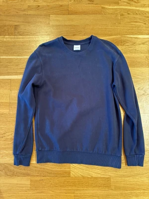Mörkblå sweatshirt från Zara - En stilren mörkblå sweatshirt från Zara med rund hals och ribbade muddar vid ärmslut och nederkant. Tröjan är enkel och passar perfekt till jeans eller joggers. Tillverkad i mjuk bomull för skön komfort hela dagen.