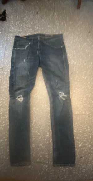 Dondup - Säljer ett par feta dondups i storlek W 31 med slitningar och trasiga detaljer vid knäna. Jeansen har klassisk femficksdesign,tillverkade i kvalitet-denimtyg. Den enda defekten är skinn ettiketten på insidan men det syns ej! 