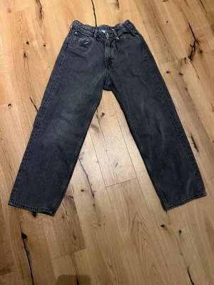 Svarta raka jeans med loose fit - Säljer ett par svarta jeans med rak passform och loose fit. Jeansen har klassisk femficksdesign, knapp och dragkedja framtill samt bälteshällor. Materialet är denim och färgen är tvättad svart för en cool, avslappnad look.