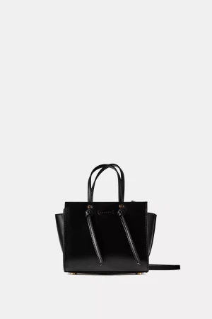 Zara KNOTTED MINI CITY BAG - Stilren svart handväska från Zara i slätt skinn med guldfärgade detaljer. Väskan har två handtag, justerbar axelrem och praktisk dragkedja upptill. Snygg boxig form med dekorativa knutar framtill och flera fack inuti för dina essentials. Som ny.