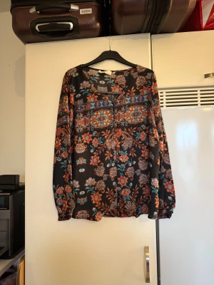 Cream skjorta  - Säljer en otroligt vacker skjorta med en vart bottenfärg och ett vacker blommig mönster. Storlek 38. Mycket fint skick, jag hittar inga synliga anmärkningar eller defekter. 