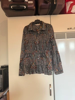 Odd molly skjorta  - Säljer en otroligt vacker skjorta med en svart bottenfärg med ett superfint mönster i massa olika färger, Från märket Odd Molly. Storlek 2 som enligt deras storleksguide motsvarar en M. Mycket fint skick, jag hittar inga synliga anmärkningar eller defekter.  