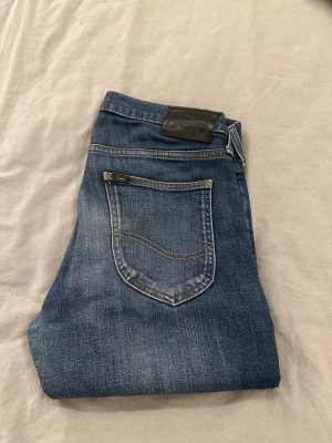 Levi's blå jeans med klassisk passform - Säljer ett par snygga blå jeans från Levi's med klassisk femficksdesign och diskret logotyp på bakfickan. Jeansen har en rak siluett och är tillverkade i slitstarkt denimtyg med snygga tvättade detaljer. Perfekt för dig som gillar tidlös stil. Strl w30 w32