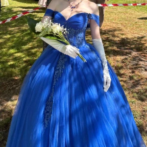 Balklänning blå - En extremt vacker balklänning använd endast en gång! Jag är osäker på storlek på klänningen då den är omsydd. Men jag skulle säga att den är för någon i storlek S eller runt det. Den är i längden för någon mellan 165-170 i klackskor, men utan klackskor skulle jag säga något kortare! Midjan är i korsett och skulle gissa på att den passar någon mellan 64-72 cm i midja. Underkjol ingår! Original pris 8900kr. Det går att diskutera pris! Jag kommer endast sälja den runt Linköping och inte via frakt!