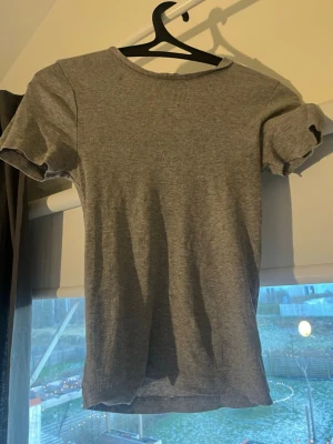 Grå ribbad topp från BikBok XS - OBS! Den har två små hål(se på sissta bilden) Säljer en enkel grå ribbad topp från BikBok i storlek XS. Toppen har rund hals, korta ärmar och är gjord i ett mjukt, stretchigt material. Perfekt att matcha med jeans eller kjol för en chill look.