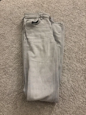 Grå jeansbyxor från 157, XS - Snygga grå jeansbyxor från 157 i storlek XS med full längd. Klassisk femficksdesign, dragkedja och knapp framtill. Byxorna har raka ben och är gjorda i mjukt bomullsmaterial med en neutral grå ton som passar till allt. Byxorna har gått sönder nertill 