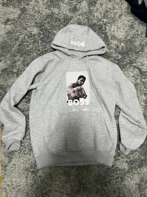BOSS x Muhammad Ali - En grå hoodie från BOSS med ett samarbete med Muhammed Ali