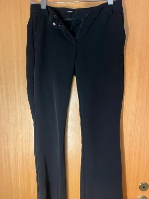 Svarta bootcut byxor från BikBok - Säljer ett par svarta bootcut byxor från BikBok i storlek 36. Byxorna har dragkedja och dubbla knappar framtill samt bälteshällor. Snygg passform med lätt utsvängda ben och klassisk look. Perfekta till en enkel topp eller hoodie.