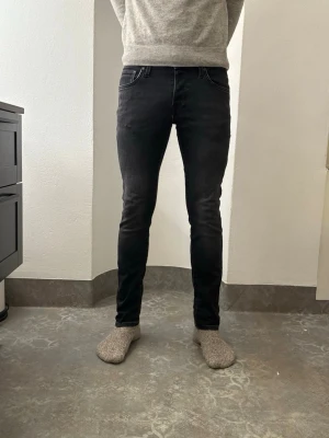 Svarta slim jeans från Jack & Jones - Säljer ett par svarta slim fit jeans från Jack & Jones, modell Glenn. Jeansen har klassisk femficksdesign, smal passform och normal midja. Materialet är mjukt och stretchigt för extra komfort. Perfekt för dig som gillar en stilren och modern look. Modellen är 184 och väger 72. 
