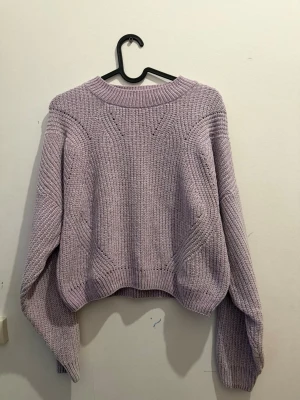 En stickad skön tröja  - Stickad tröja i lila nyans med strukturstickning. Använd fåtal gånger och i fint skick. Mjuk och bekväm, perfekt till vardag eller höst/vinter. Kortare modell med långa ärmar som ger en trendig passform. Storlek: 14+Y Passar även XS/S beroende på kroppstyp och hur man vill att den ska sitta.